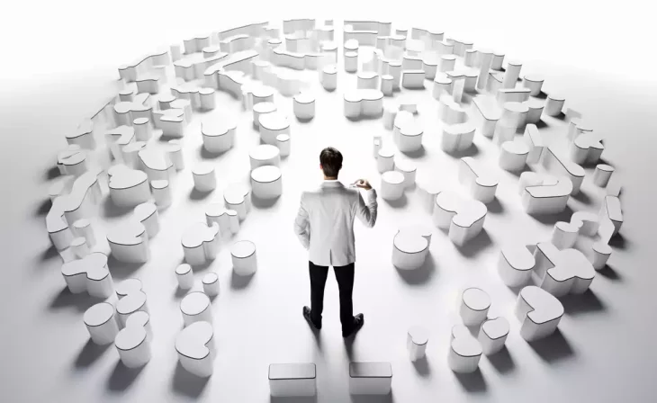 an in white shirt observing a vast array of white, 3D puzzle pieces arranged in a circular pattern. Asset vs Share Purchase