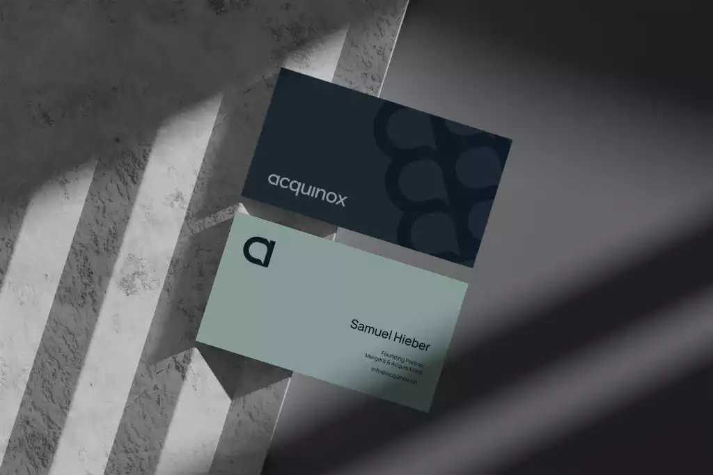 Acquinox business card with dark blue and light green design, displaying the name 'Samuel Hieber' and contact details, placed on a textured gray background with light shadows.