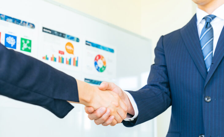 Handshake between two businessmen indicating a successful merger of companies.